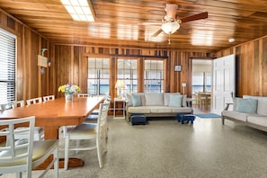 Una habitación con paneles de madera, una mesa de comedor, sillas, un sofá y un ventilador de techo.