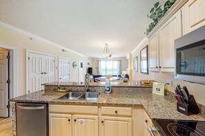 A kitchen with granite countertops, stainless steel appliances, and a sign indicating a fire extinguisher. - Wonderful 5th-floor condo in Gulf-front building with pool & central AC (Panama City Beach)