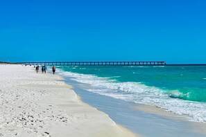 A beach with a pier extending into the ocean, sandy shore, and people walking along the beach. - Dog-friendly home near the beach with private pool, Ping-Pong, foosball & bikes (Navarre)