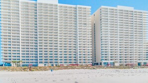 Ett högt hotell med flera våningar, balkonger och utsikt över stranden.