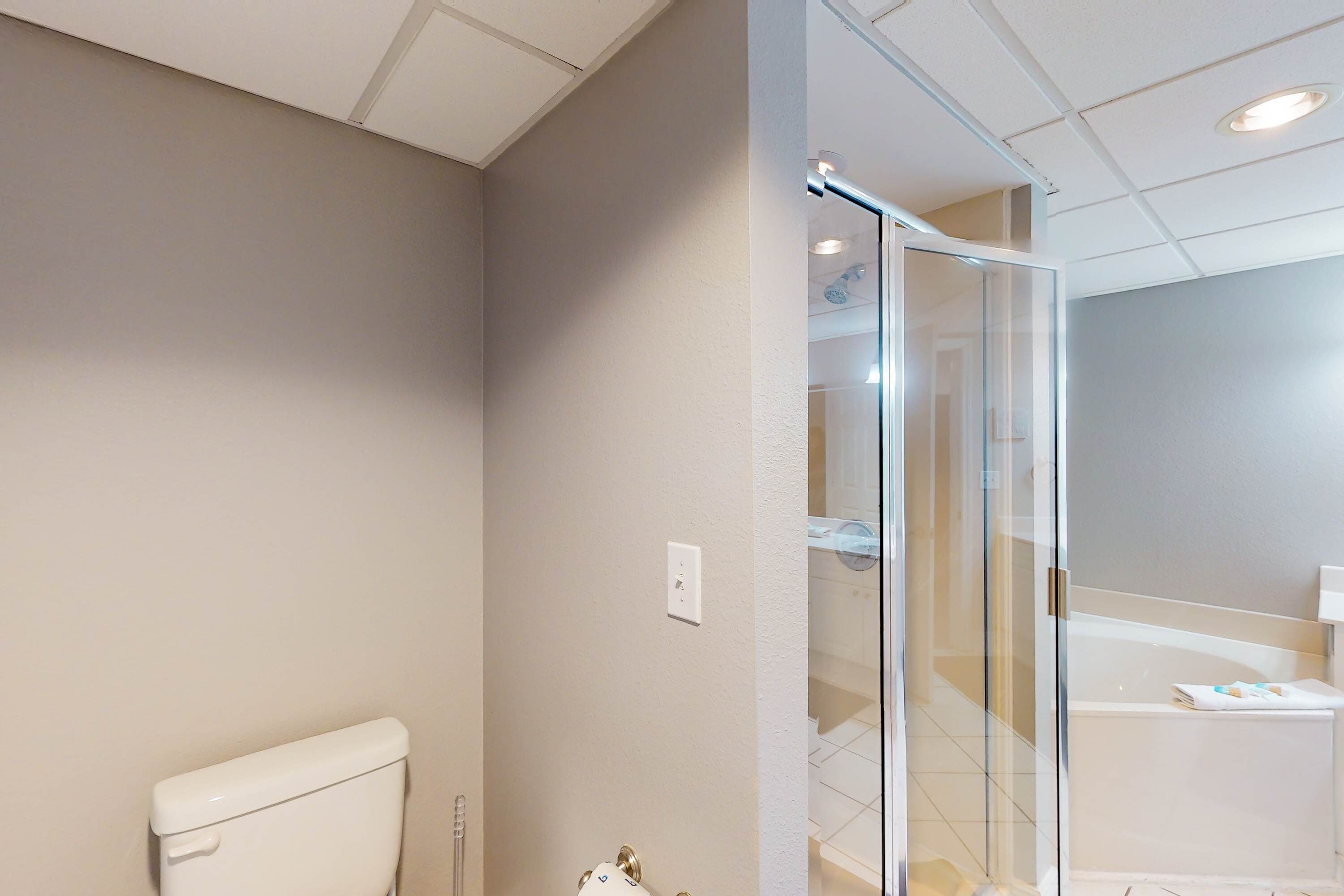 A modern bathroom with a toilet, a glass shower enclosure, and a bathtub.