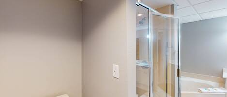 A modern bathroom with a toilet, a glass shower enclosure, and a bathtub.