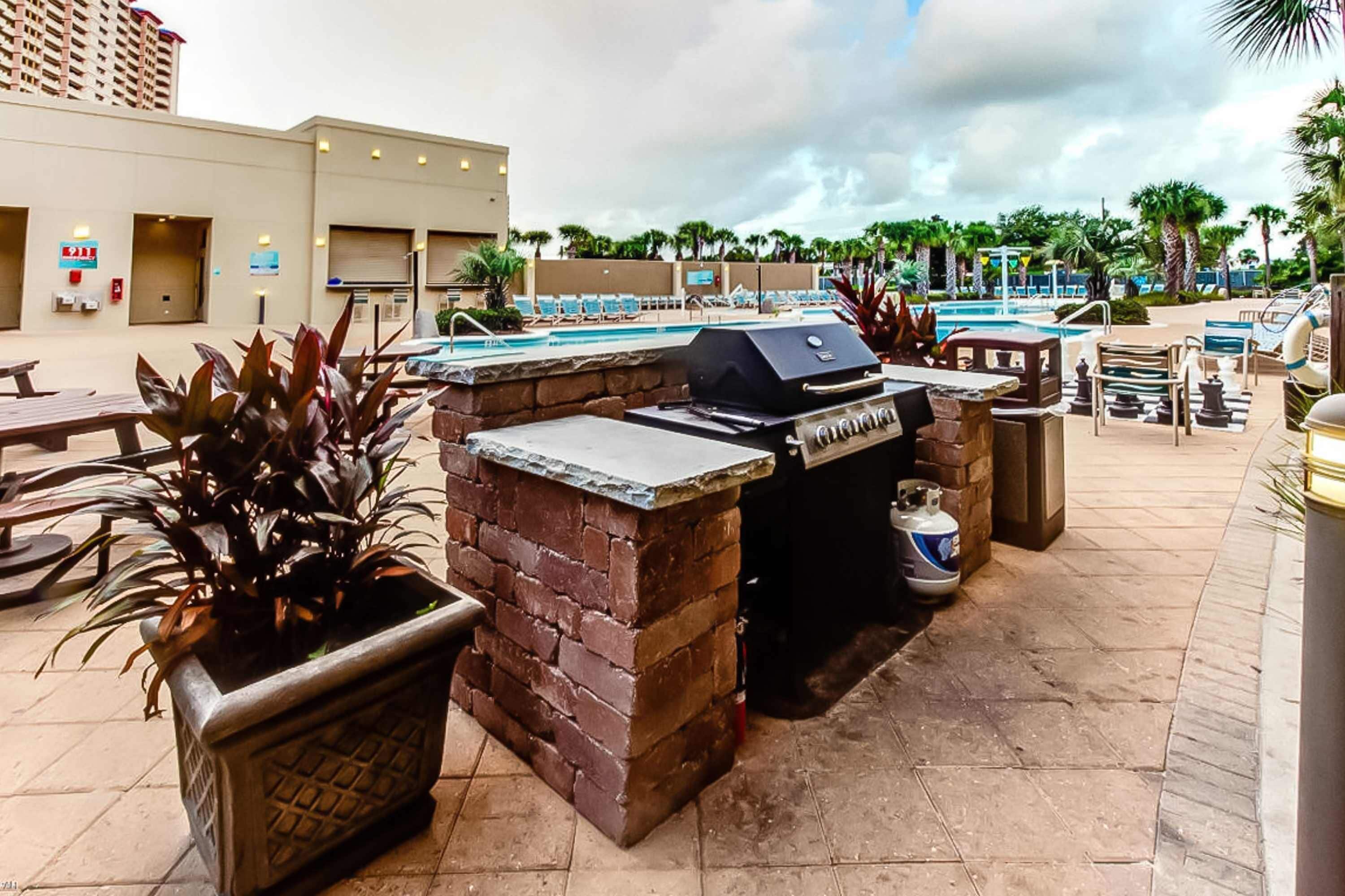 Un espace extérieur avec piscine, un coin barbecue, des chaises longues et un jardin en briques agrémenté de plantes.
