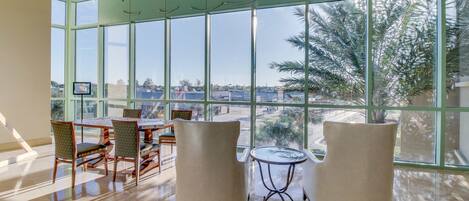 A spacious room with large windows, a dining area with chairs and a table, and a small round table with chairs.