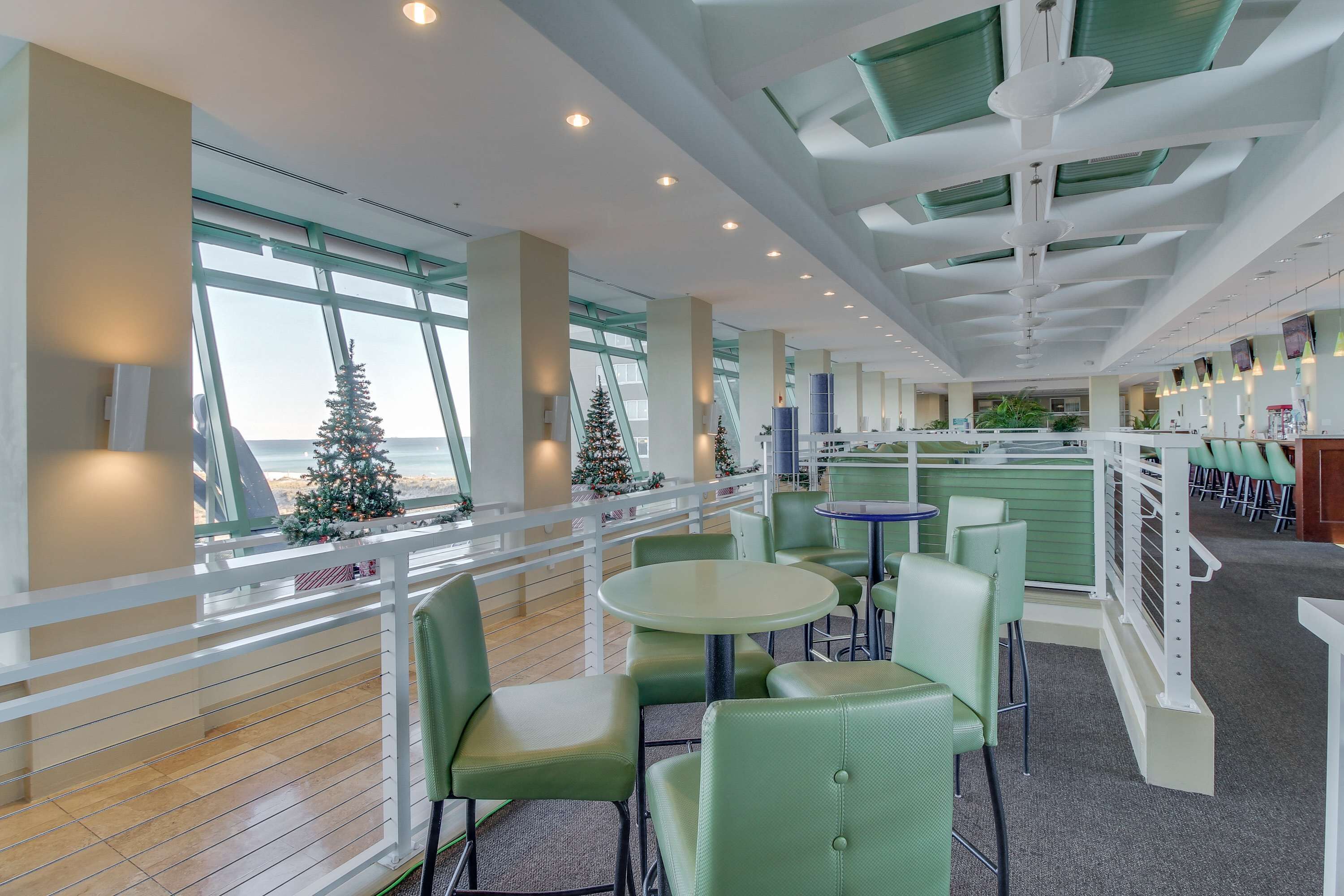 A spacious indoor area with green seating, large windows, and a view of the outside.