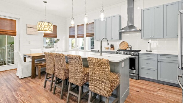A modern kitchen with a central island, bar stools, and a stainless steel range hood. - Modern beachside haven with LSV and gas grill - bike to Blue Mt Beach (Santa Rosa Beach)