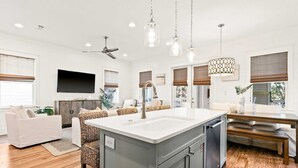 A modern kitchen with a central island, wooden flooring, and pendant lighting. - Modern beachside haven with LSV and gas grill - bike to Blue Mt Beach (Santa Rosa Beach)