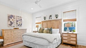 A bedroom with a large bed, wooden headboard, and a dresser with drawers. - Modern beachside haven with LSV and gas grill - bike to Blue Mt Beach (Santa Rosa Beach)
