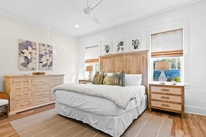 A bedroom with a large bed, wooden headboard, and a dresser with drawers. - Modern beachside haven with LSV and gas grill - bike to Blue Mt Beach (Santa Rosa Beach)