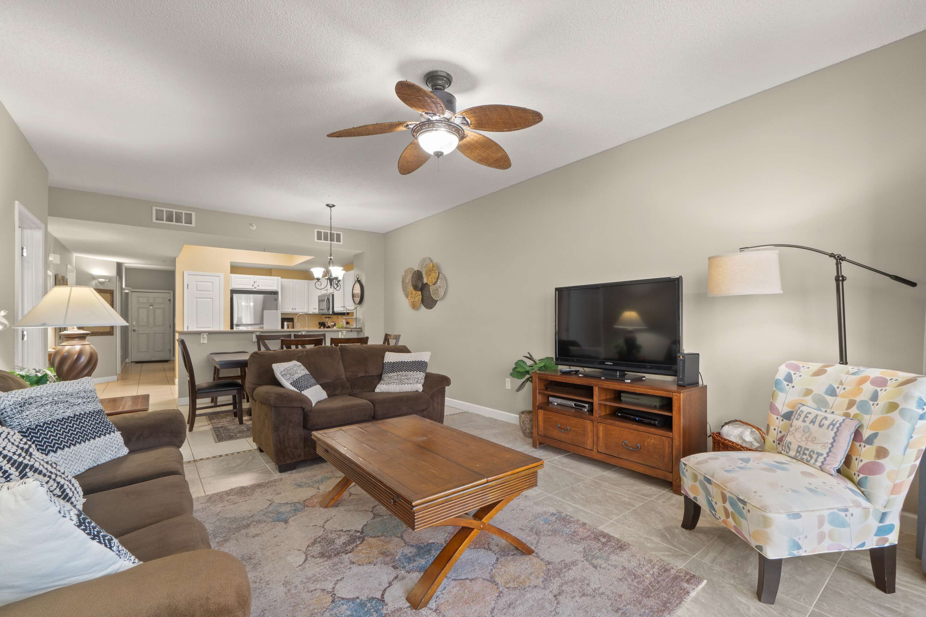 A living room with a sofa, coffee table, TV, and a patterned armchair.