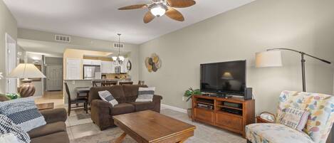 A living room with a sofa, coffee table, TV, and a patterned armchair.