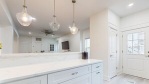 A modern kitchen with a large marble countertop, white cabinetry, and pendant lighting. - Beautiful dog-friendly condo, private washer&dryer and close to beach (Navarre)