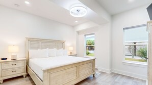 A bedroom with a large bed, two bedside tables, a ceiling light, and a window with a view of greenery. - Beautiful dog-friendly condo, private washer&dryer and close to beach (Navarre)
