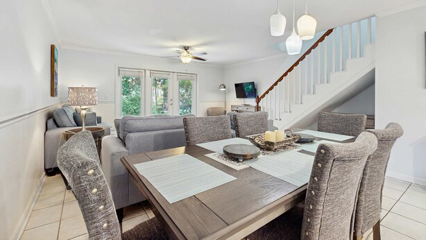 A dining area with a wooden table, grey upholstered chairs, and hanging pendant lights. - Lakefront Duplex with High-Speed Wi-Fi, Short Walk to Beach, and Water View (Santa Rosa Beach)