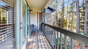 A wooden deck with a railing, a door with a lattice design, and a view of a forest. - Lakefront Duplex with High-Speed Wi-Fi, Short Walk to Beach, and Water View (Santa Rosa Beach)