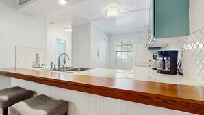 A modern kitchen with a wooden countertop, stainless steel sink, and bar stools. - Lakefront Duplex with High-Speed Wi-Fi, Short Walk to Beach, and Water View (Santa Rosa Beach)