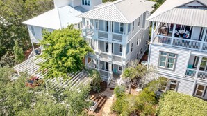 A multi-story house with a porch and a deck, surrounded by trees.