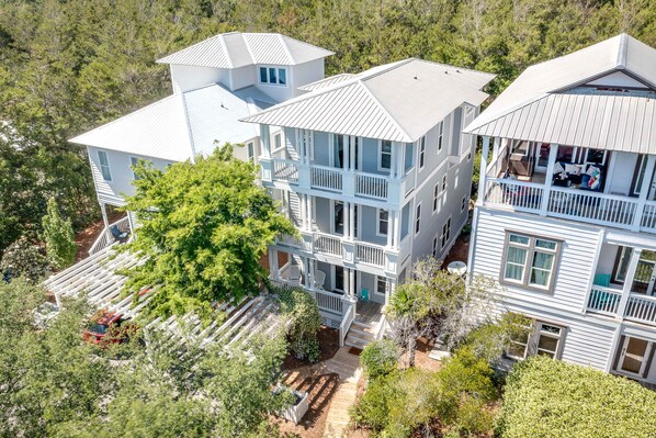A multi-story house with a porch and a deck, surrounded by trees. - 3-level home with 2 decks, patio, grill, hot tub & pool - walk to private beach (Seacrest)