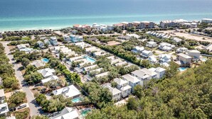 A coastal residential area with multiple houses, some with swimming pools, and a view of the ocean.