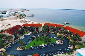 Vista aérea de un hotel costero con estacionamiento, acceso a la playa y un muelle.