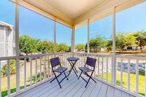 A covered outdoor area with a white railing, two folding chairs, and a small table. - Charming home with enclosed sunroom, porch, central AC, & W&D - near beach (Santa Rosa Beach)