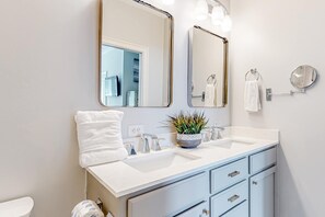 A modern bathroom with a white sink, two mirrors, a towel rack, and a potted plant. - Charming home with enclosed sunroom, porch, central AC, & W&D - near beach (Santa Rosa Beach)