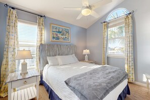 A bedroom with a bed, two bedside tables with lamps, a ceiling fan, and curtains. - Gulf-front house near golf with pool, ocean views, beach access, & balcony (Inlet Beach)