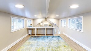 A room with a sloped ceiling, a desk, a chair, and a window with blinds. - Peaceful & sun-soaked getaway with fire pit & W&D - near beaches, trails, & golf (Navarre)