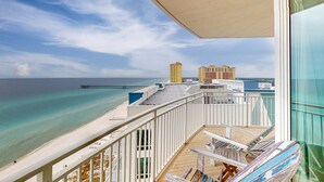 A balcony with a view of the beach and ocean, a wooden deck, and a glass railing. - 16th-floor condo with Gulf views, beach access, 2 pools, hot tub, & private W&D (Panama City Beach)