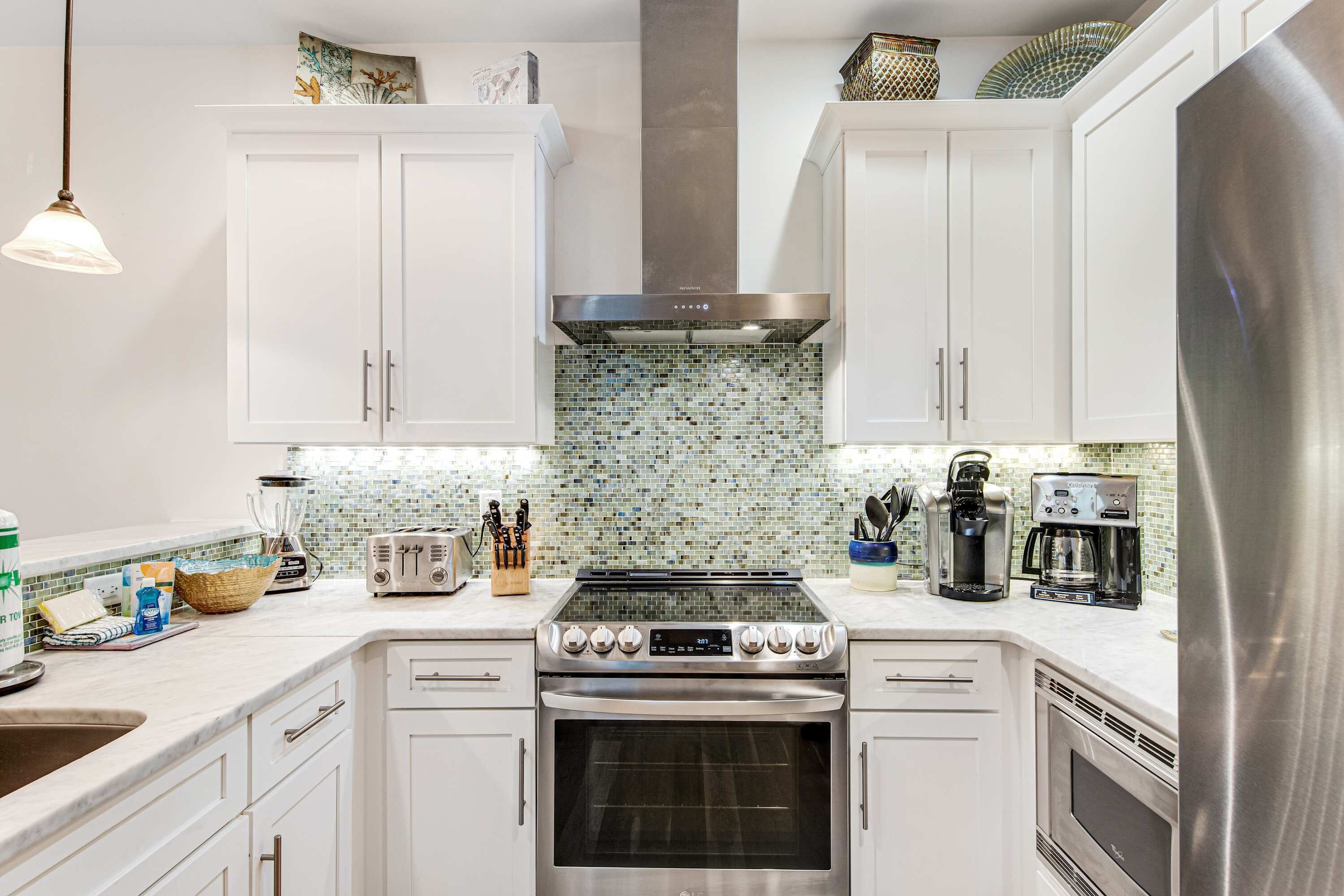 A modern kitchen with white cabinets, a stainless steel range, and a tiled backsplash.