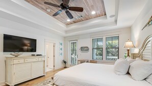 Un dormitorio con una cama grande, un ventilador de techo, un televisor y una ventana con persianas.