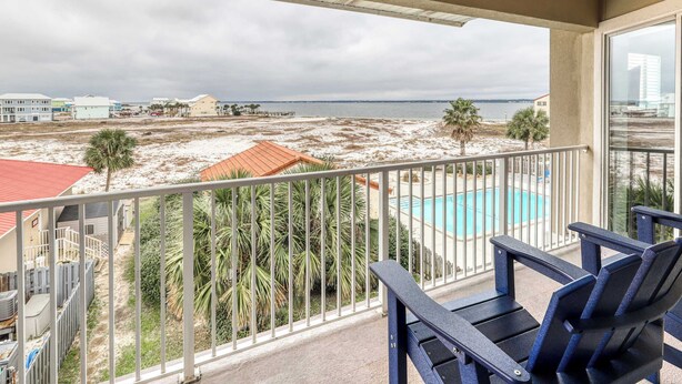 Ein Balkon mit Blick auf einen Strand, ein Schwimmbad und Palmen.
