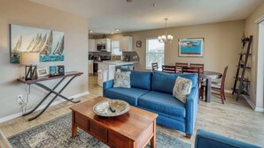 Ein geräumiges Wohnzimmer mit einem blauen Sofa, einem Holztisch und einem Essbereich mit Tisch und Stühlen.