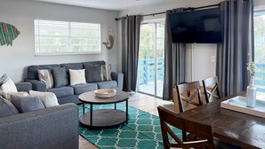 A living room with a sofa, coffee table, and dining table. - Gorgeous home with private pool, outdoor space and close to beach (Panama City Beach)