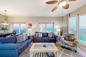 A spacious living room with a large sofa set, a coffee table, and a view of the ocean. - Gulf-front condo with never-ending views, hot tub & pool access, balcony, & W&D (Panama City Beach)