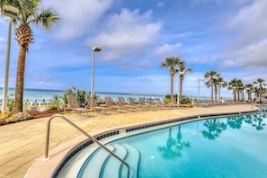 A poolside area with lounge chairs, palm trees, and a view of the ocean. - Gulf-front condo with never-ending views, hot tub & pool access, balcony, & W&D (Panama City Beach)