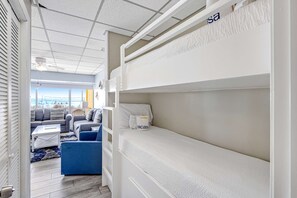A modern hotel room with a bunk bed, a sofa, and a coffee table. - Beachfront condo with central AC, WiFi, access to pool, washer&dryer (Panama City Beach)