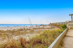 A beach with a wooden walkway and a palm tree. - Beachfront condo with central AC, WiFi, access to pool, washer&dryer (Panama City Beach)
