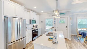 A modern kitchen with white cabinetry, stainless steel appliances, and a central island. - Newly built dog-friendly home with spacious backyard & private W&D (Panama City Beach)