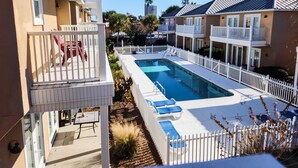 A pool area with a white fence, lounge chairs, and a table. - Spacious house with patio, pool, balcony, deck, & W&D - beach access (Panama City Beach)