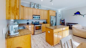 A modern kitchen with wooden cabinets, stainless steel appliances, and a granite countertop. - Spacious house with patio, pool, balcony, deck, & W&D - beach access (Panama City Beach)