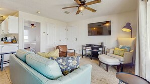 A living room with a ceiling fan, a sofa, a coffee table, and a TV.