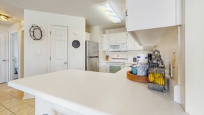 A modern kitchen with white cabinetry, a central island, and a microwave.