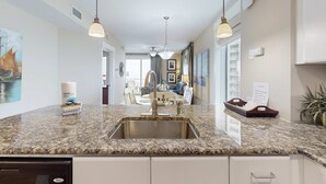 Eine Küche mit Granit-Arbeitsplatten, Spüle aus Edelstahl und Pendelleuchten.