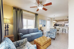 Ein Wohnzimmer mit einer Couch, Sesseln, einem Couchtisch und einem Deckenventilator.