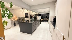 A modern kitchen with a central island, white tiled flooring, and a checkered floor pattern in the background. - Dreamy Stay With Cosy Charm (Addlestone)