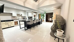 Une cuisine moderne avec des meubles blancs, un îlot central noir et un coin repas avec des chaises.