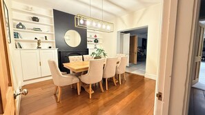 Un coin repas avec une table et des chaises en bois, un mur d’accent de couleur noire et un miroir rond au-dessus de la table.