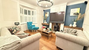 A living room with two sofas, a coffee table, a blue armchair, a fireplace, and a TV. - Dreamy Stay With Cosy Charm (Addlestone)