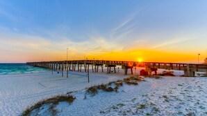 Ein Strand mit einer hölzernen Steg, der ins Meer führt, bei Sonnenuntergang.